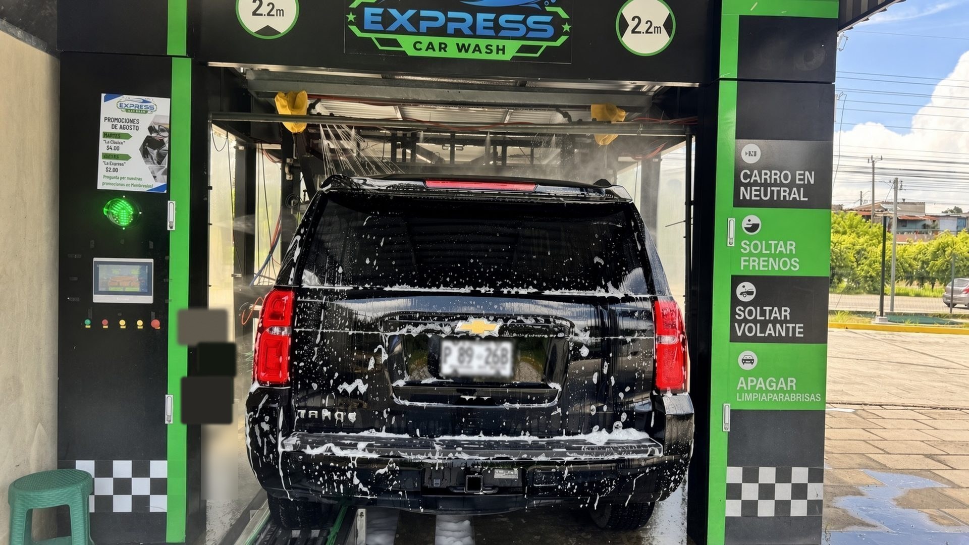 Túnel de autolavado en operación en El Salvador, con un SUV negro cubierto de espuma.